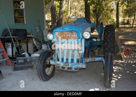 Il vecchio trattore Ford siede sotto un fienile. Foto Stock