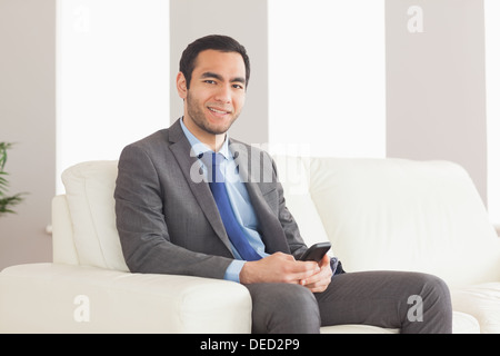 Imprenditore sorridente seduto sul divano accogliente Foto Stock