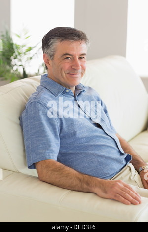 Uomo sorridente seduto su un divano Foto Stock