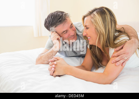 Felice coppia giacendo su un letto e cercando di ogni altro Foto Stock