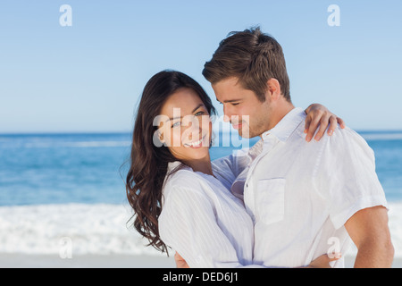 Coppia giovane abbracciando e in posa sulla spiaggia Foto Stock