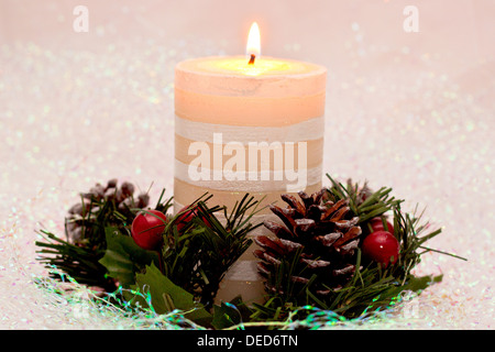 Un acceso yule candela per Natale circondato da un anello di agrifoglio Foto Stock