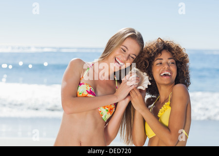 Due amici a ridere mentre si tiene conch Foto Stock