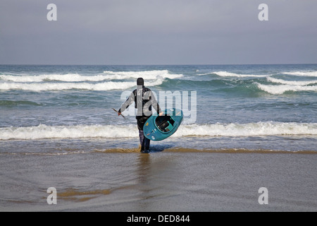 Un kayaker si prepara a cavalcare il surf sulla costa dell'Oregon, Oregon Coast vicino Yachats. Foto Stock