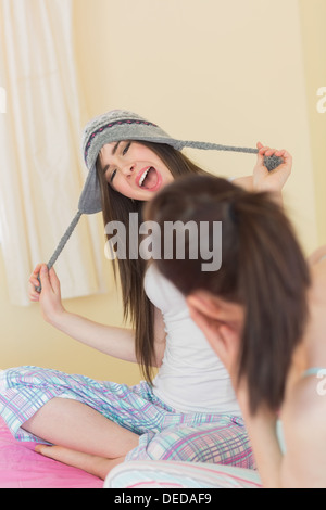 Funny Pretty girl cercando su un cappello di lana per il suo amico ridere Foto Stock