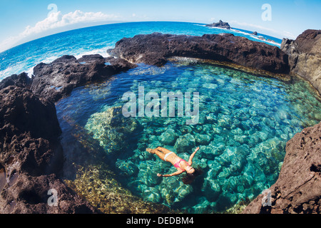 Attraente giovane donna galleggianti in etereo bella piscina naturale Foto Stock