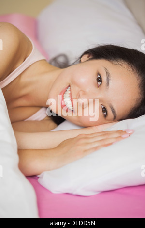 Piuttosto giovane donna asiatica che giace nel suo letto sorridente Foto Stock