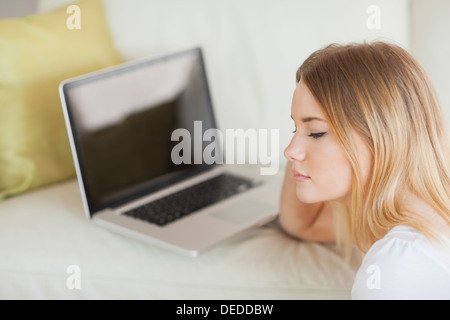 Premurosa donna seduta sul pavimento nella parte anteriore del computer portatile Foto Stock