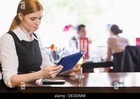 Imprenditrice guardando lo schermo tablet tenendo bicchiere da vino Foto Stock