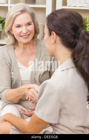 Una commessa con mano tremante con un senior donna a casa Foto Stock
