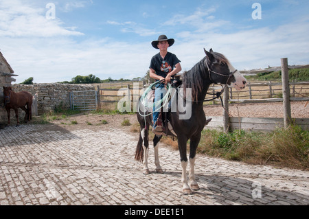 Giovani cowboy seduti su un cavallo con un lazo Foto Stock