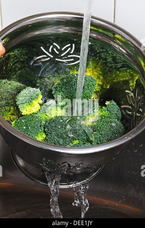 Broccoli di risciacquo in un colapasta sotto l'acqua corrente. Foto Stock