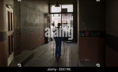 Berlino, Germania, un uomo vecchio con le stampelle a piedi attraverso una porta Foto Stock