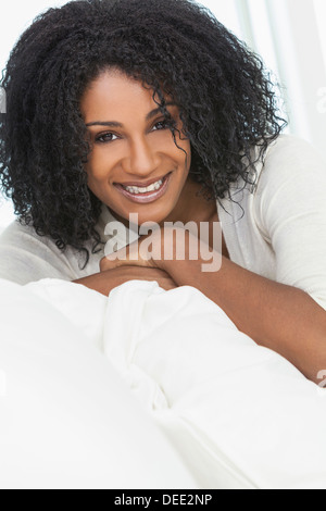 Ritratto di un bellissimo centro di età americano africano donna seduta a casa rilassarsi sorridendo o ridendo Foto Stock