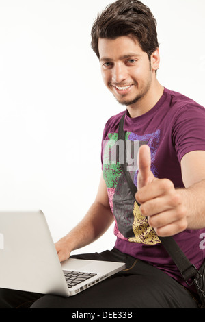 Giovane maschio lavora su laptop pollice in alto Foto Stock