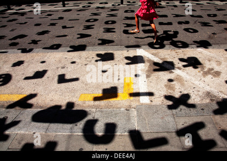 Ragazza in abito rosa saltando lungo la strada, Gracia, Barcellona, Spagna. Foto Stock
