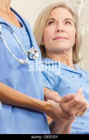 Senior donna femmina paziente in un letto di ospedale avente il suo impulso prese da una femmina di un infermiere o un medico Foto Stock