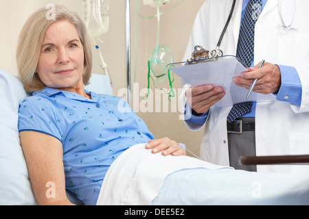 Senior donna femmina paziente in un letto di ospedale essendo curata da un infermiere o un medico Foto Stock