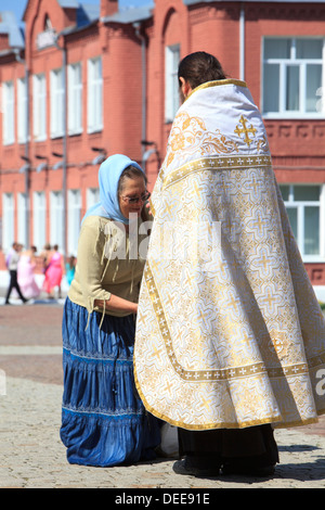 Una signora anziana prestando il suo rispetto a un Orientale sacerdote ortodosso in Kolomna, Russia Foto Stock