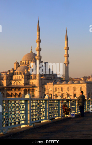 Pescatore sul Ponte Galata con nuova moschea in background, Istanbul, Turchia, Europa Foto Stock