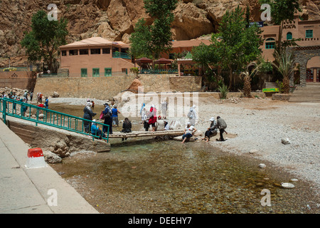 Turisti e gente locale rinfrescante nel fiume in Todra, Marocco Foto Stock