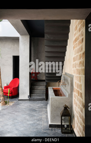 Lavandino e poltrona rossa nel cortile della casa di Marrakech Foto Stock