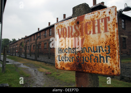 Segno "vorsicht hochspannung lebensgefahr' è nella parte anteriore di alcuni elettrificata di recinzioni perimetrali. Foto Stock
