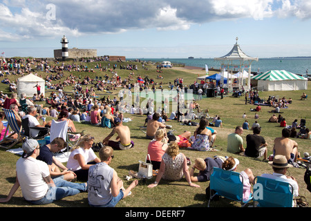 La folla si riunisce intorno al chiosco Southsea per assistere a uno spettacolo dal vivo di una band locale. Southsea Castello in background. Hampshire, Inghilterra Regno Unito Europa Foto Stock