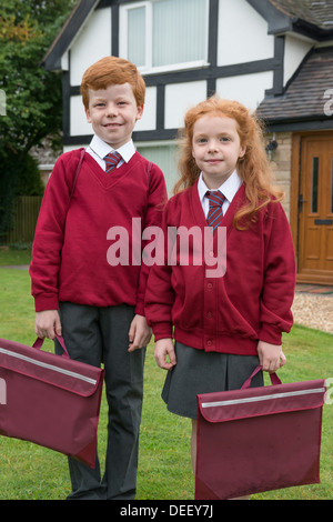 Fratello e Sorella nella loro uniforme scolastica al di fuori della loro casa. Foto Stock
