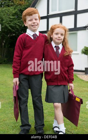 Fratello e Sorella nella loro uniforme scolastica al di fuori della loro casa. Foto Stock