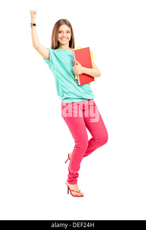A piena lunghezza Ritratto di un felice studentessa contenere libri e gesticolando felicità Foto Stock