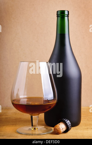 Vetro e bottiglia di cognac con sughero su uno sfondo di legno Foto Stock