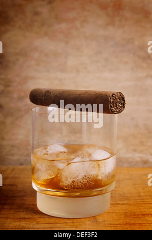 Bicchiere di whiskey e sigari su un annata sullo sfondo di legno Foto Stock