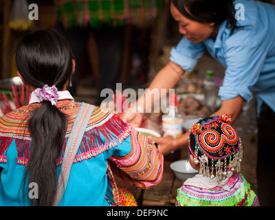 Un fiore donna Hmong e suo figlio sono serviti pranzo presso la domenica mattina il mercato di Bac Ha, Lao Cai Provincia, Vietnam. Foto Stock