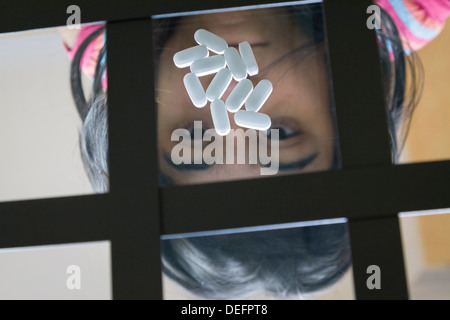 Una giovane donna fissando compresse Foto Stock