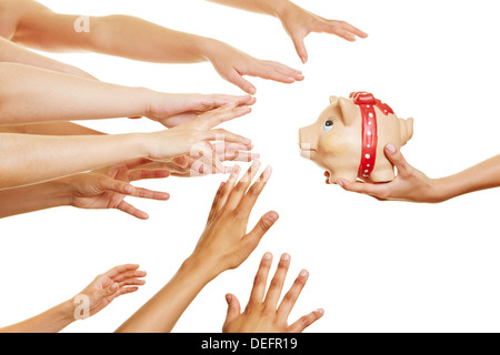 Molte mani per raggiungere il denaro in un salvadanaio in una mano Foto Stock