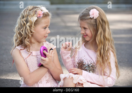 Due giovani ragazze preteen indossando rosa e putting fanno fino a. Foto Stock