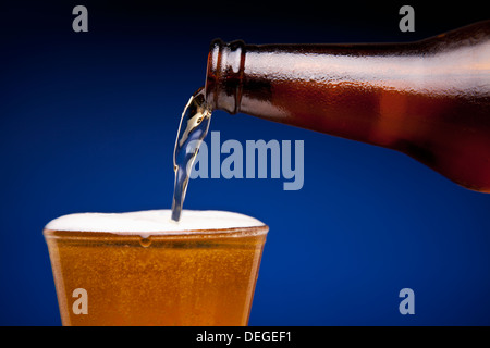 La birra viene versata in un bicchiere. Foto Stock