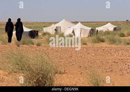 Due donne dalla famiglia nomade, indossando la mulafa, mauritane abito tradizionale, tornare indietro a piedi alla loro tented home nel deserto Foto Stock