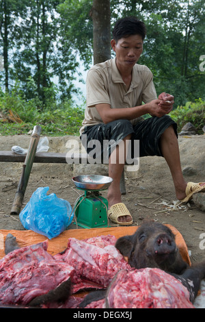 Nero uomo Hmong vendita del bestiame carni di suino sul modo di Sa Pa, Lao Cai, Vietnam Foto Stock