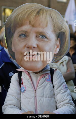 Dublino, Irlanda. 18 settembre 2013. Un manifestante indossa una maschera di grandi dimensioni raffigurante il Cancelliere tedesco Angela Merkel. I manifestanti di tenere un assemblea popolare al di fuori del Dail (Parlamento irlandese), per discutere di austerità in gruppi più piccoli. Il gruppo era parte di una giornata di proteste di coincidere con il ritorno del TDS (membri del parlamento) dal loro pausa estiva. Credito: Michael Debets/Alamy Live News Foto Stock