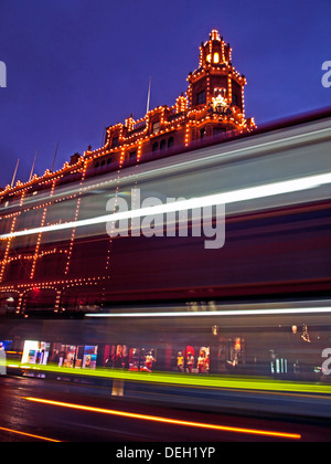 Sfocato double-decker bus davanti ai grandi magazzini Harrods di notte, Knightsbridge, Royal Borough di Kensington e Chelsea Foto Stock