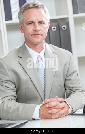 Uomo o imprenditore seduto alla scrivania in ufficio moderno Foto Stock