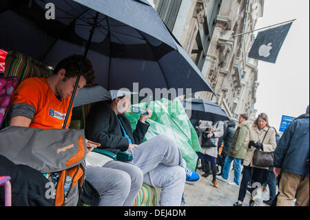 Londra, Regno Unito. Xix Sep, 2013. La coda per il lancio di Apple i-phone 5 huddles sotto gli ombrelli sotto la pioggia. Credito: Guy Bell/Alamy Live News Foto Stock