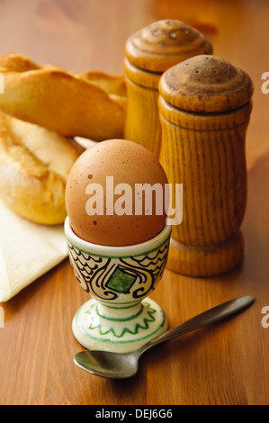 La prima colazione all'uovo con sale e pepe e il pane su un sfondo di legno Foto Stock