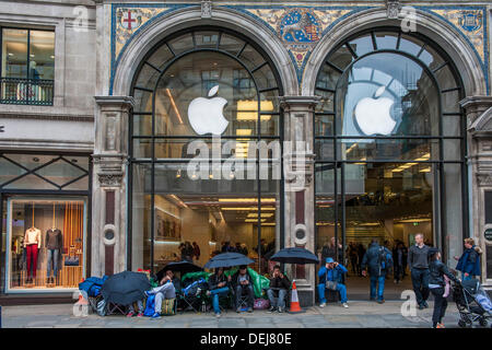 Londra, Regno Unito. Xix Sep, 2013. La coda per il lancio di Apple i-phone 5 huddles sotto gli ombrelli sotto la pioggia. Esso è costituito da queste persone e una manciata dietro l'angolo. Il lancio di un nuovo prodotto come infausto come le condizioni meteorologiche? Ma nonostante il dato numerico apatia pochi hanno perso non opportunità di spigolare freebies di vestiti e cibo per aiutare a rendere il loro soggiorno "pagare". La maggior parte sono state anche offerto denaro per salvare il luogo per qualcun altro. Pochi potrebbero rivelare se essi avevano accettato. Mentre principalmente noioso vi è un flusso costante di giornalisti e passanti a chattare con. Credito: Guy Bell/Alamy Live News Foto Stock