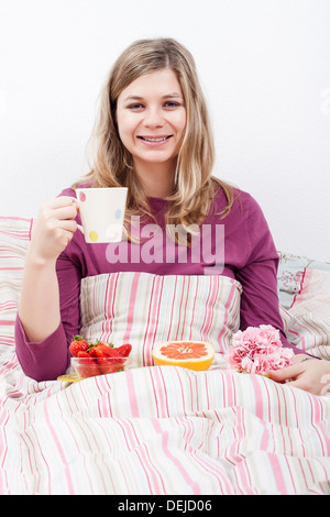Donna felice con la tazza di caffè e una romantica colazione a letto. Foto Stock