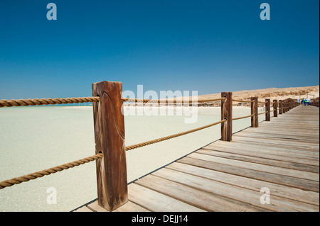 Lungo pontile in legno su un isola tropicale che si protende nella distanza Foto Stock