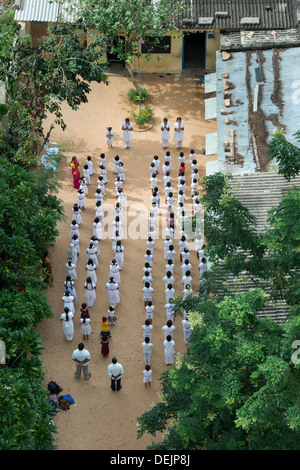 Guardando verso il basso su un Indiano inglese scuola media e i bambini della scuola di fare le preghiere del mattino in assemblea. Puttaparthi, Andhra Pradesh, India Foto Stock