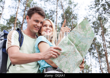 Felice giovani escursionismo giovane azienda mappa con donna rivolto lontano forest Foto Stock